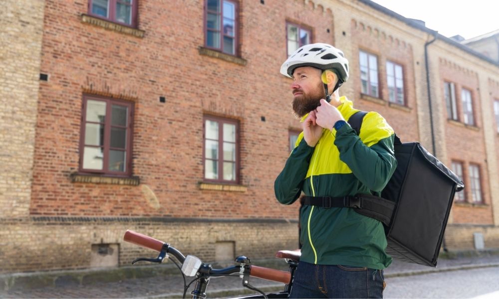 Food delivery worker straps on helmet before delivery food by bicycle