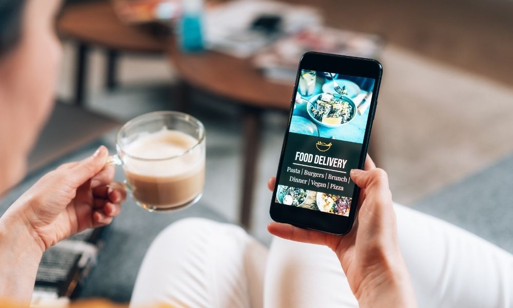 Food delivery app being used by lady on sofa