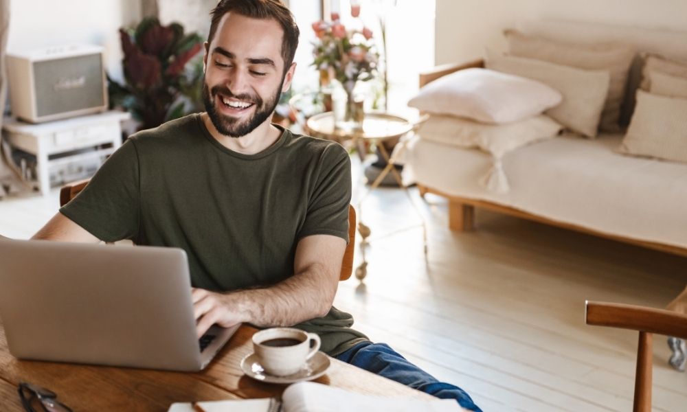 Man working from home on kitchen table with a coffee