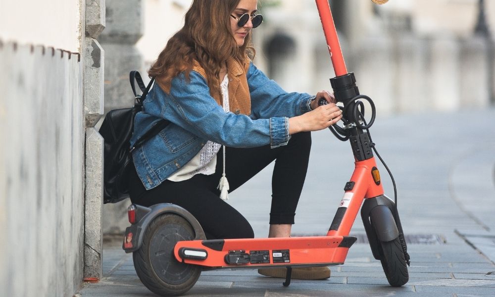 Lady unlocking an orange E-scooter being unlocked