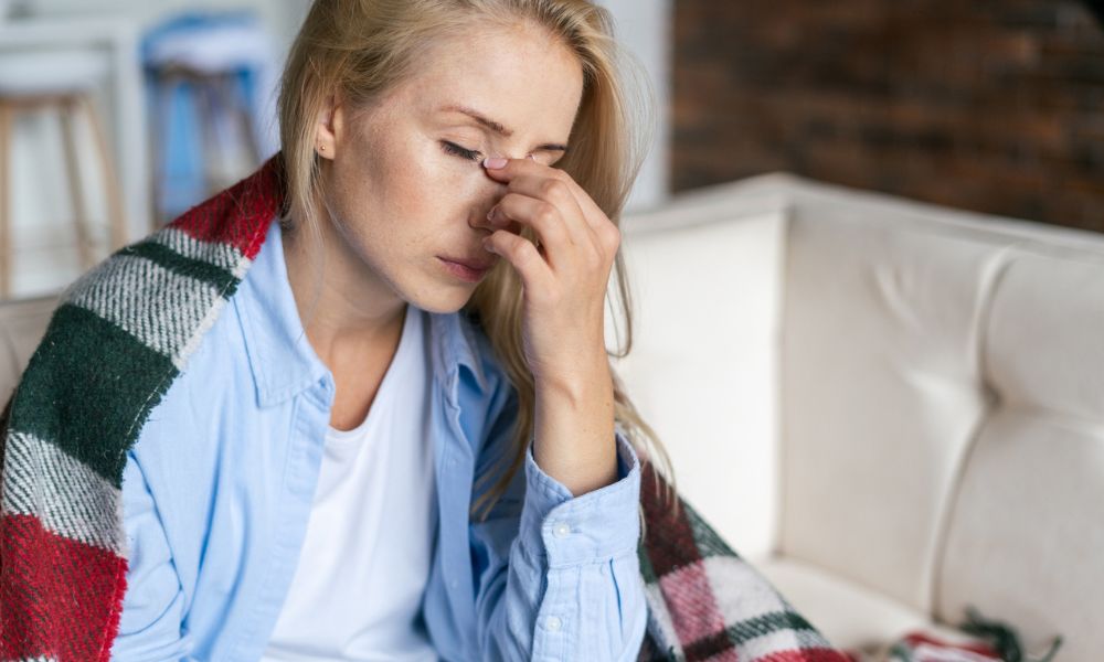 Lady on sofa looking uncomfortable in pain with hand on her face