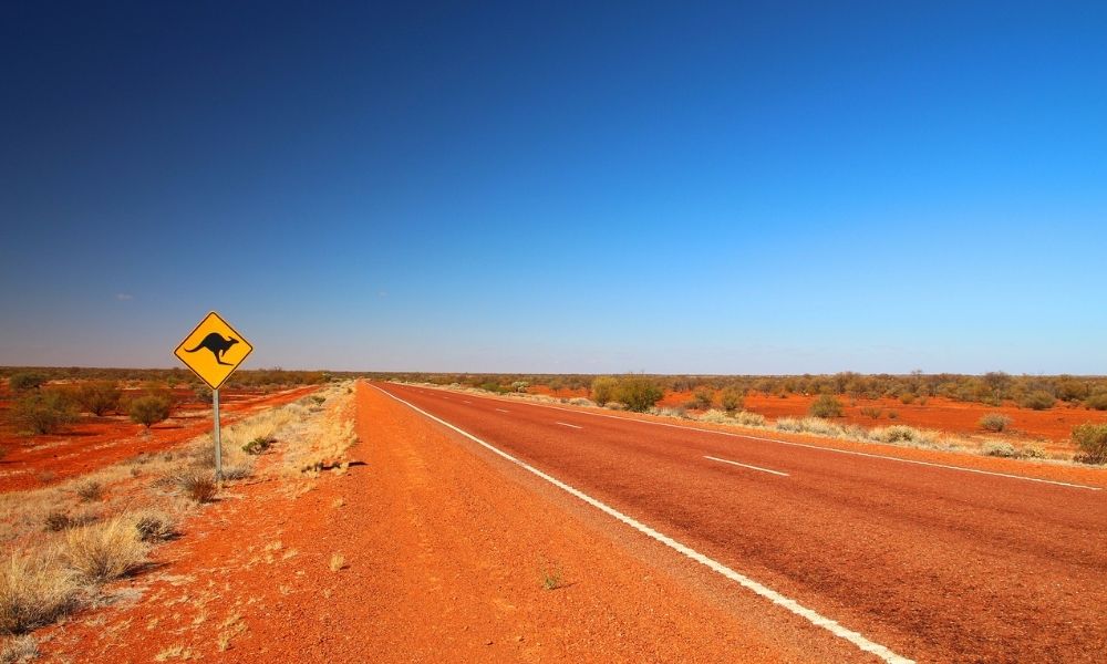 Photo of Sturt Highway in Northern Territory, Australia with red dust and Kangaroo warning sign