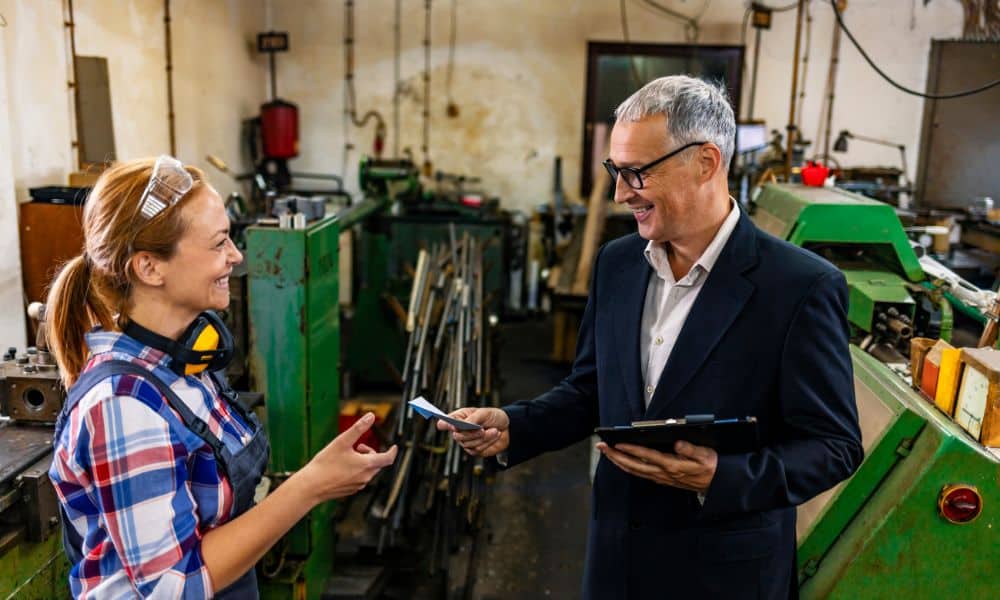 Female US worker in workshop getting workplace safety initiative award from employer